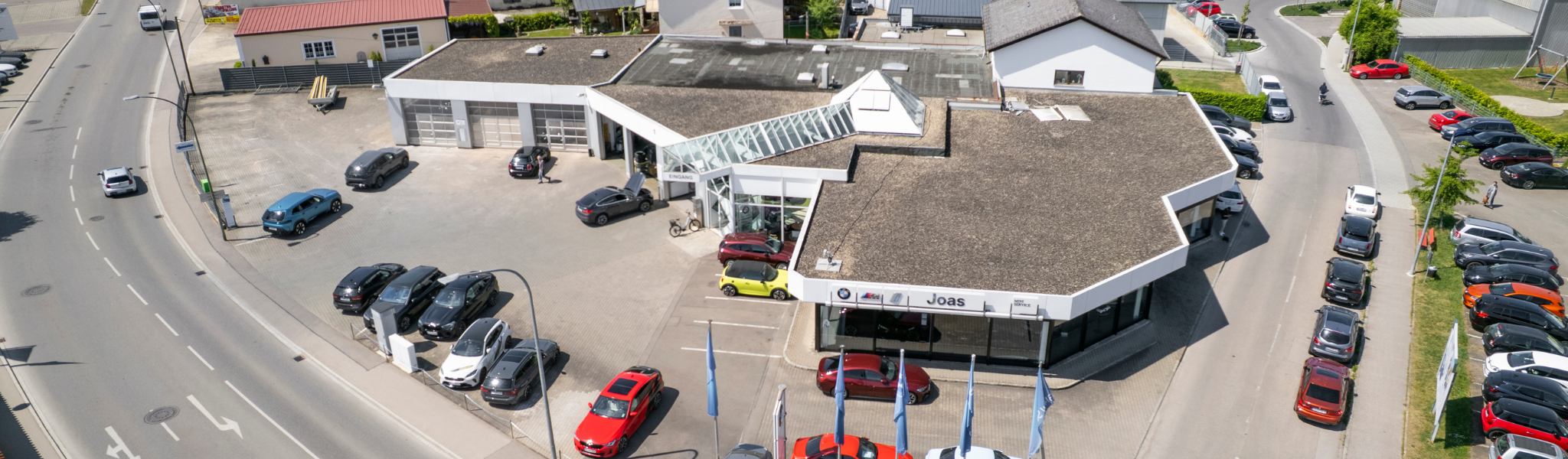 Luftaufnahme eines Autohauses mit verschiedenen ausgestellten Rädern & Reifen im Sonnenlicht.