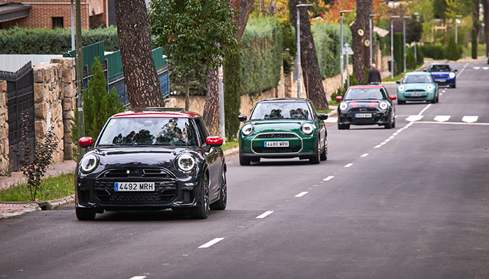 Vier Mini Cooper folgen in einer Reihe, vorbei an Steinmauern.