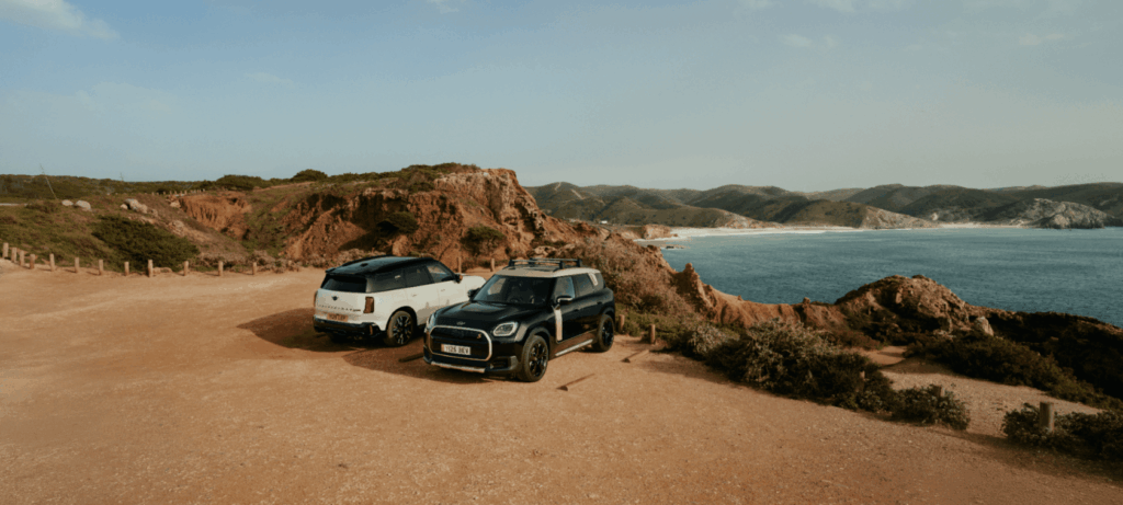 Zwei Geländewagen parken an einer Küstenklippe und genießen nach aufregenden Aktionen den Blick auf das Meer.