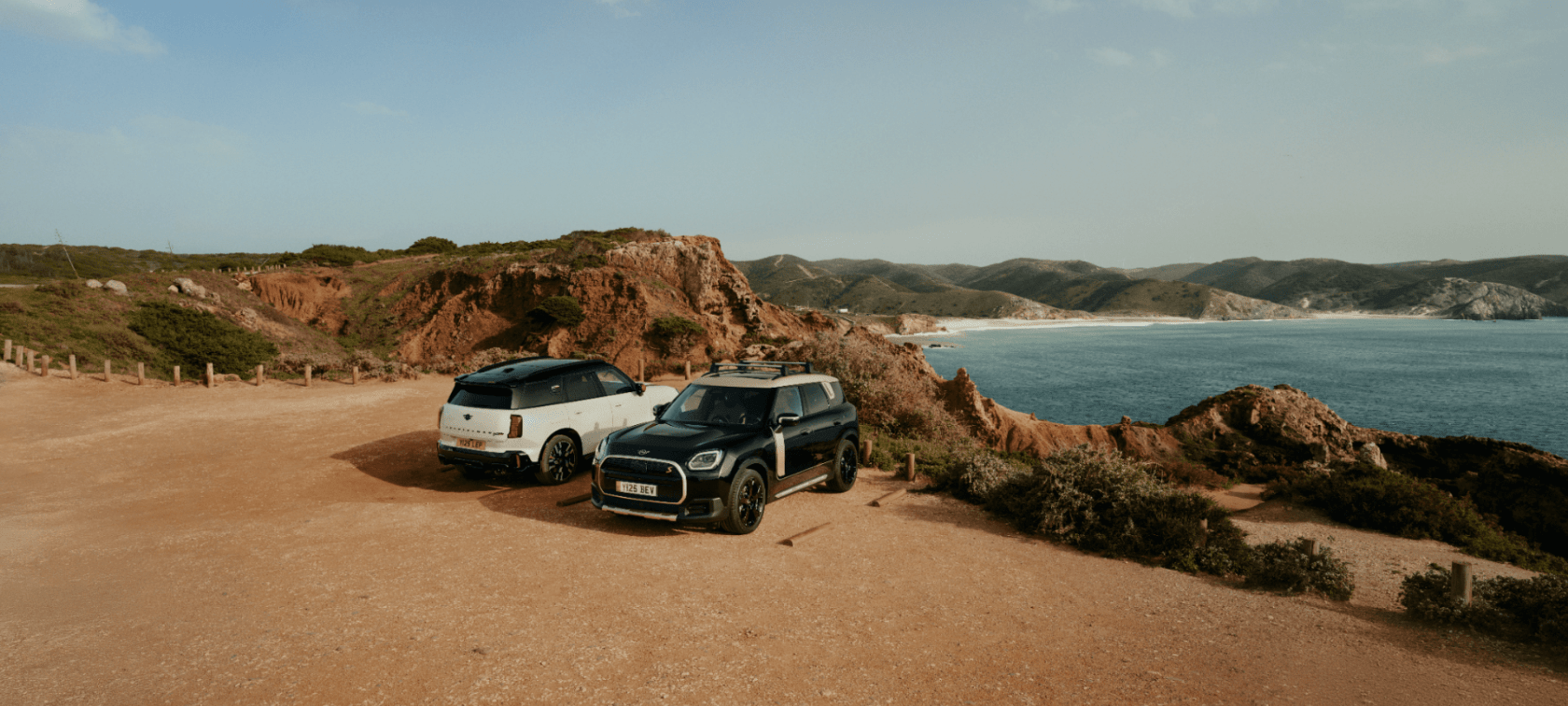 Zwei Geländewagen parken an einer Küstenklippe und genießen nach aufregenden Aktionen den Blick auf das Meer.