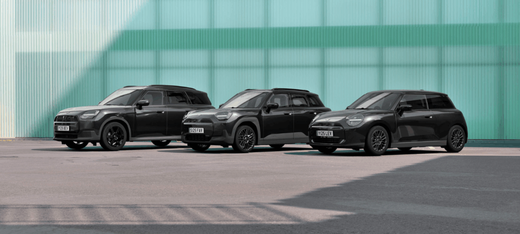 Drei schwarze MINI Autos vor grünem Hintergrund.