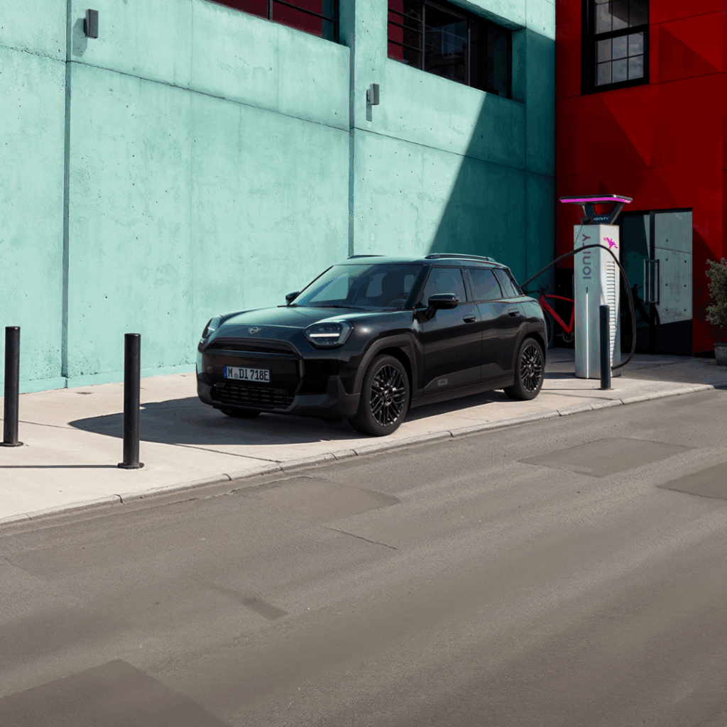 Ein vollelektrischer schwarzer MINI Aceman J05 steht auf der Straße in einer Innenstadt.