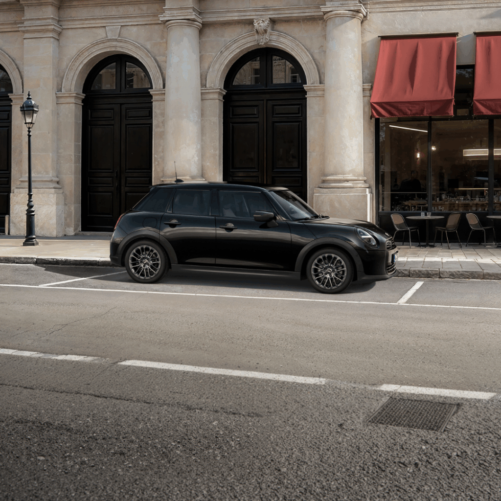 Ein schwarzer MINI Cooper F65 steht auf der Straße in einer Innenstadt.