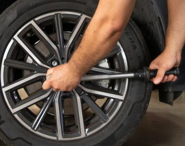 Mechaniker zieht die Radmuttern von Räder & Reifen mit einem Schraubenschlüssel in einer Werkstatt an.