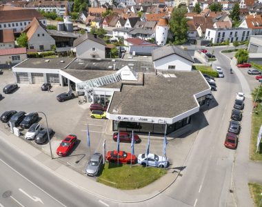 Luftaufnahme eines Autohauses in Dillingen an der Donau mit vor dem Haus geparkten Autos in einer Kleinstadt.